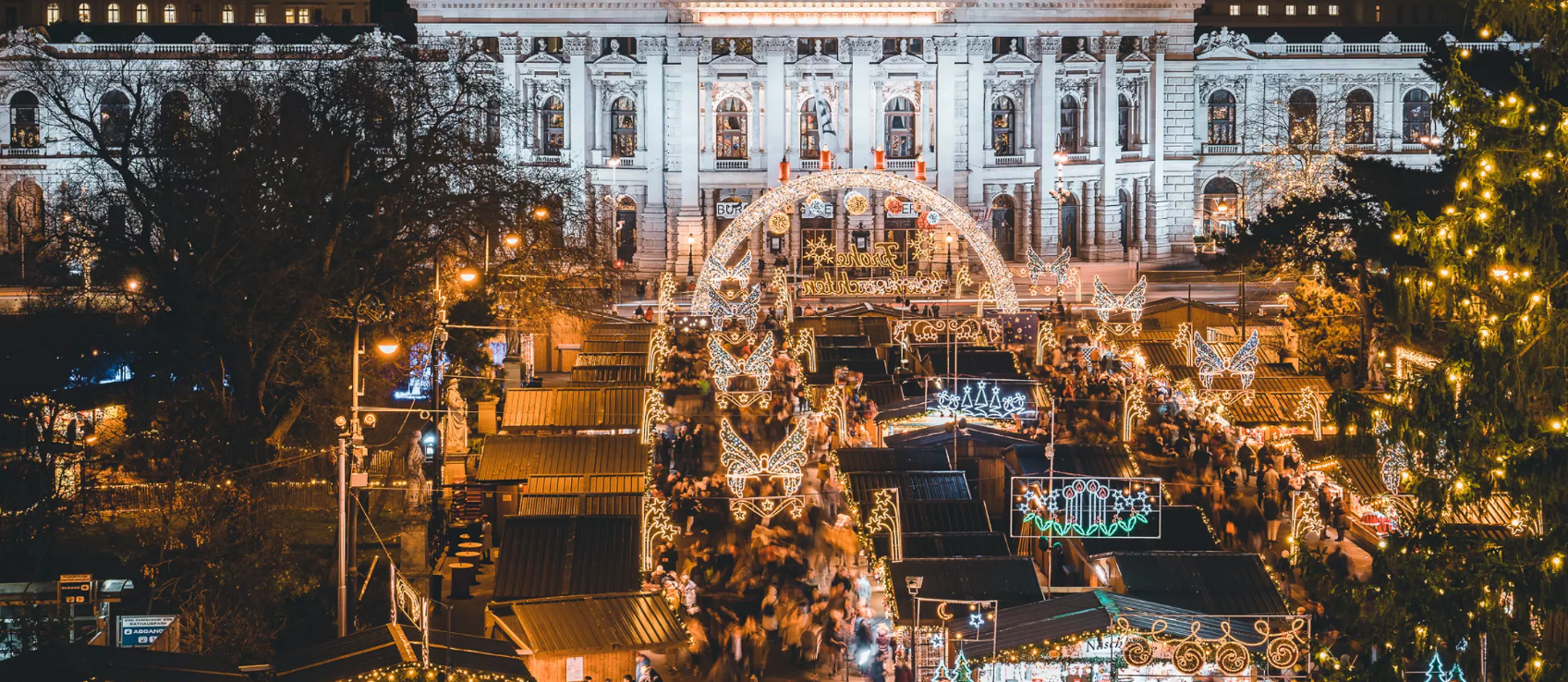 Mercado de Natal de Viena na Rathausplatz com arcos de anjos iluminados e a Rathaus ao fundo
