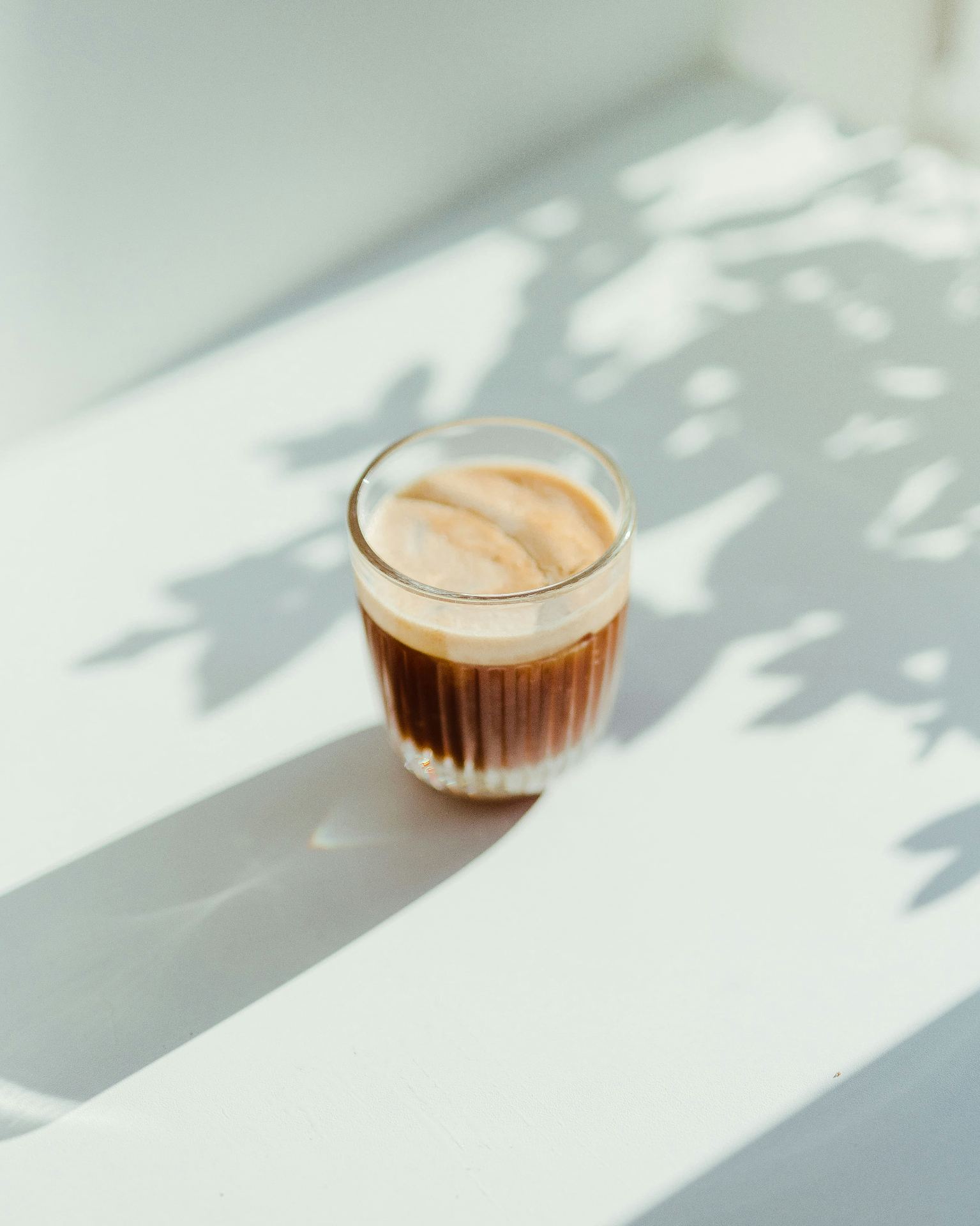 Café expresso português com crema dourada em copo de vidro - tradição diária em Portugal