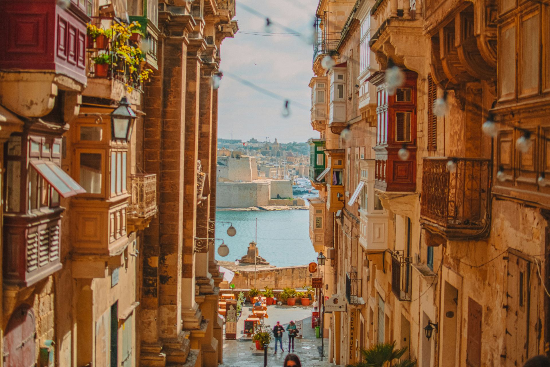 Calle histórica de La Valeta con balcones coloridos y vista al mar