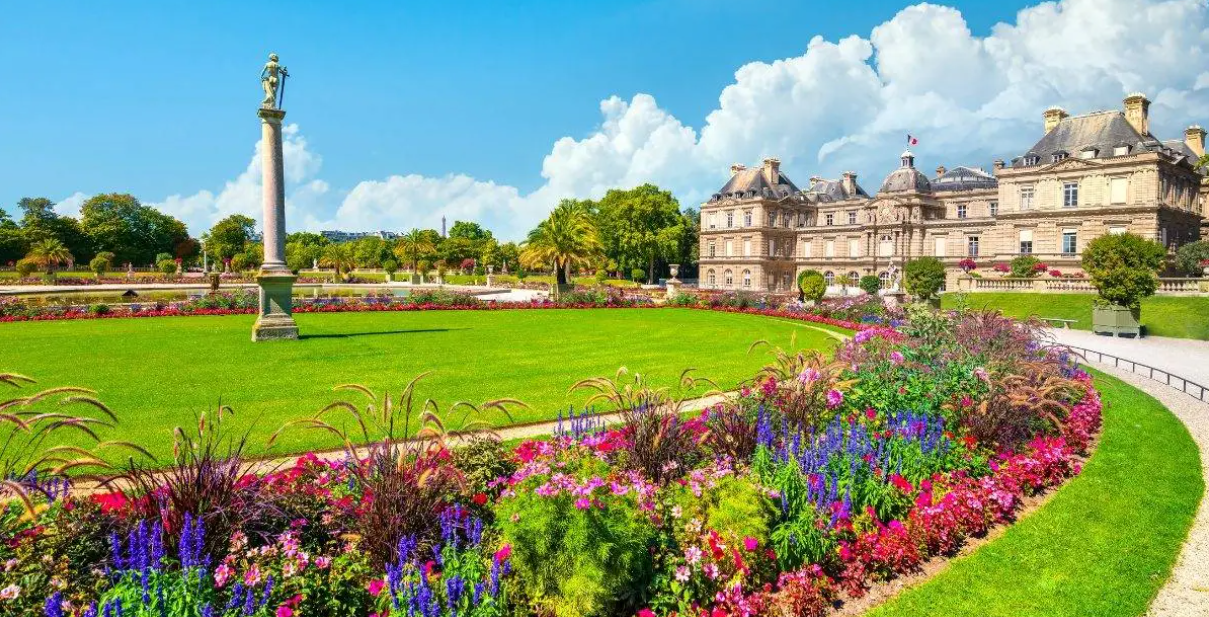 Jardim de Luxemburgo com canteiros floridos e palácio ao fundo