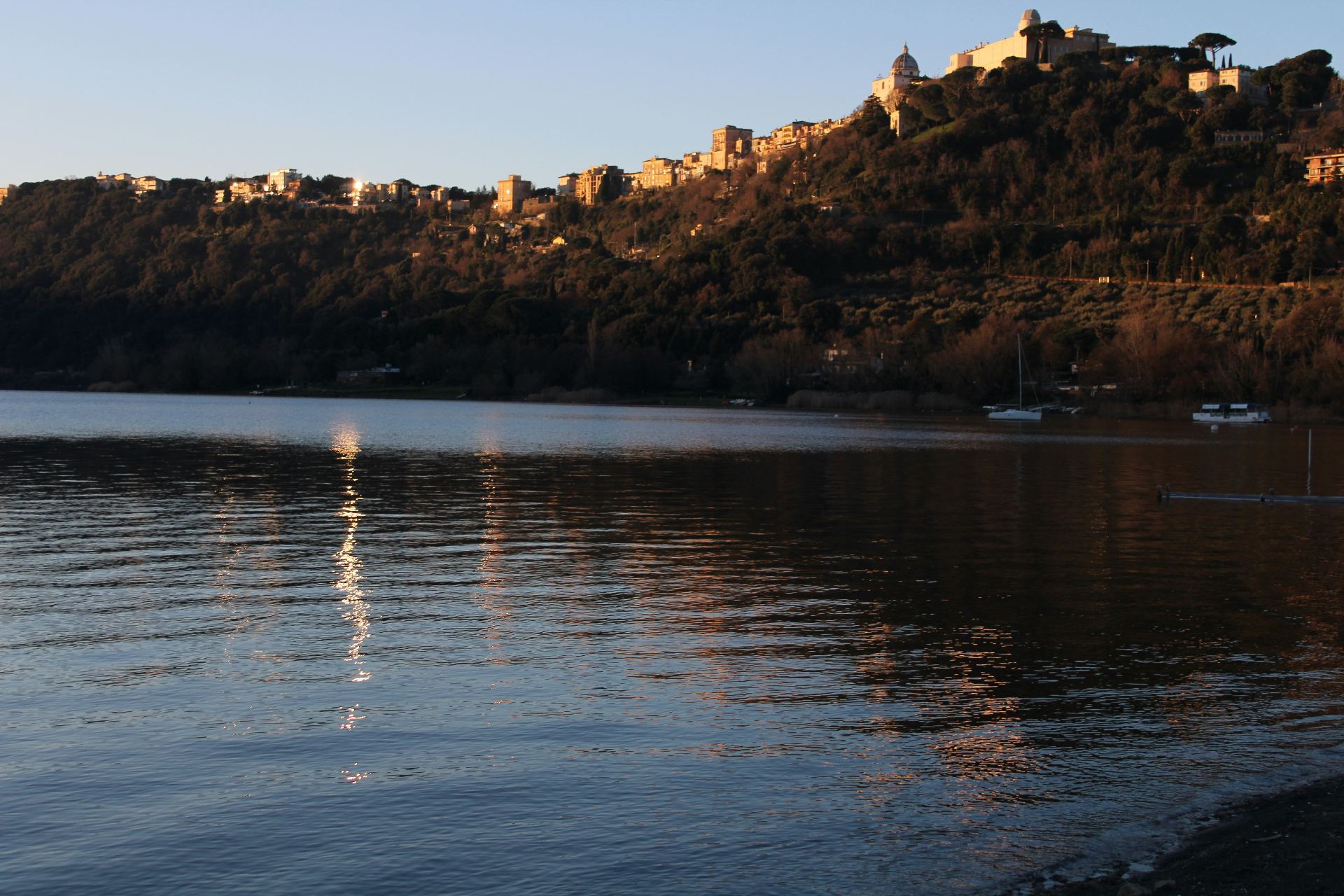 View of Lake Albano with the city of Castel Gandolfo in the background during sunset