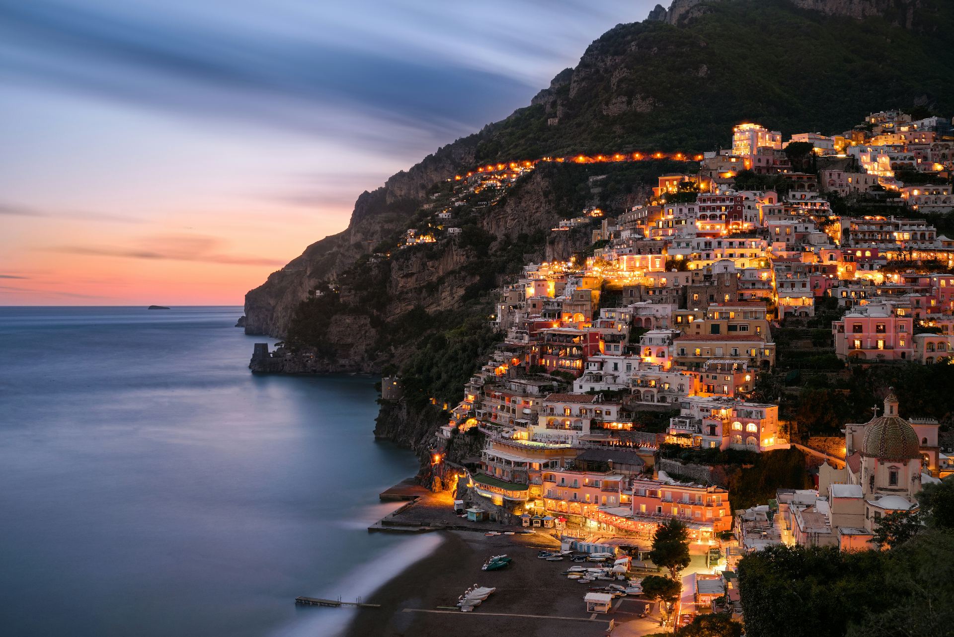Positano on the Amalfi Coast at dusk with its colorful illuminated houses