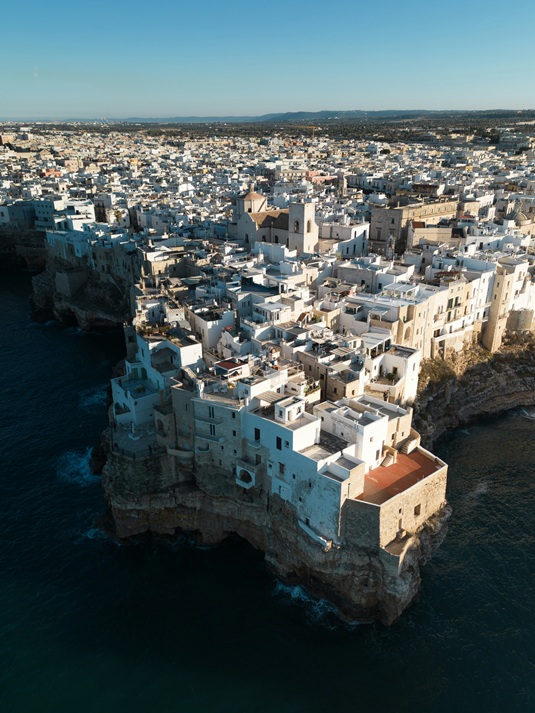 Polignano a Mare durante o dia, com casas brancas sobre as falésias e o mar Adriático turquesa
