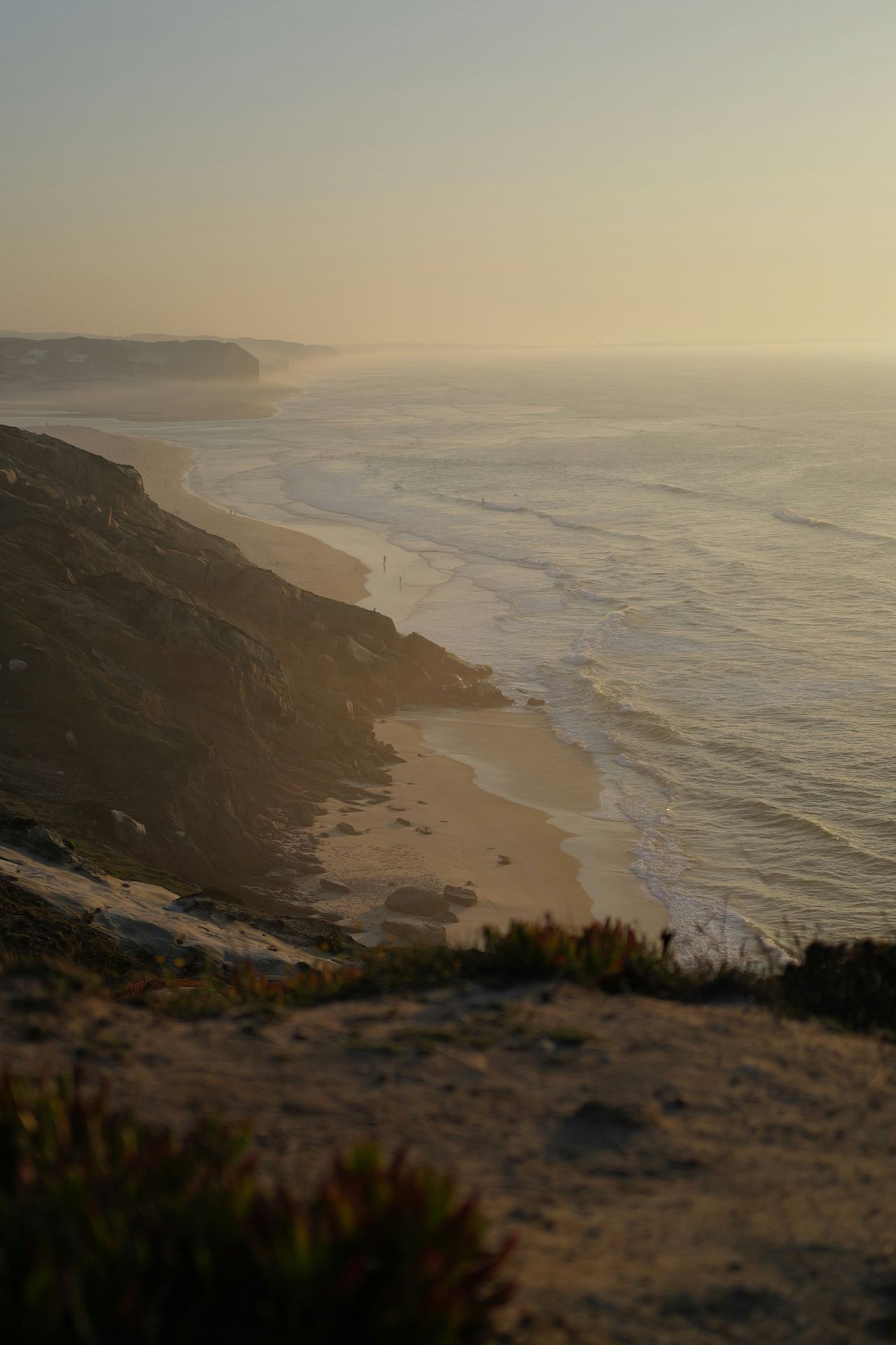 Praia da Foz do Arelho ao entardecer com ondas suaves e névoa atlântica