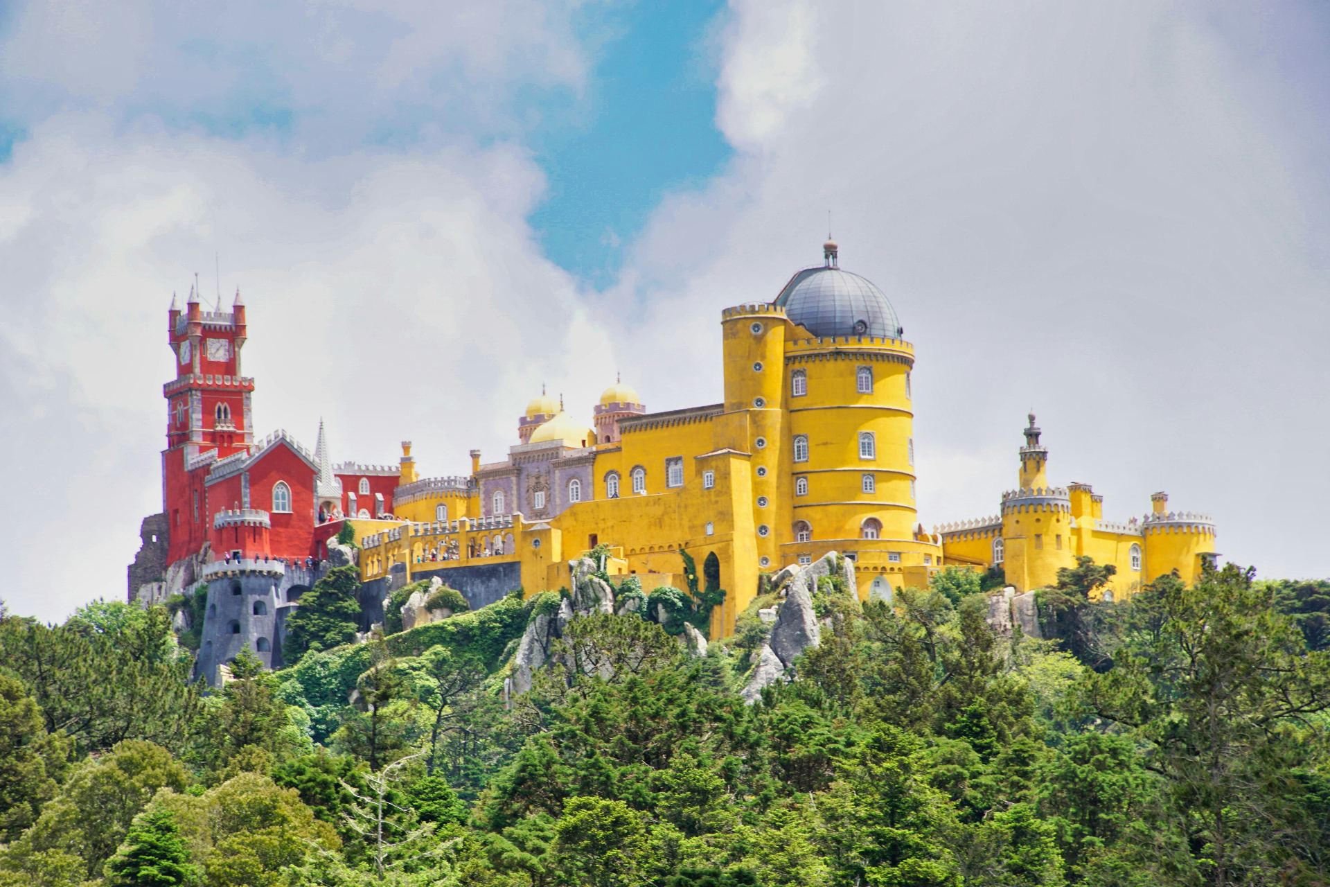 Palácio da Pena em Sintra com as suas cores vibrantes amarelo e vermelho, torres românticas e cúpulas contra o céu azul