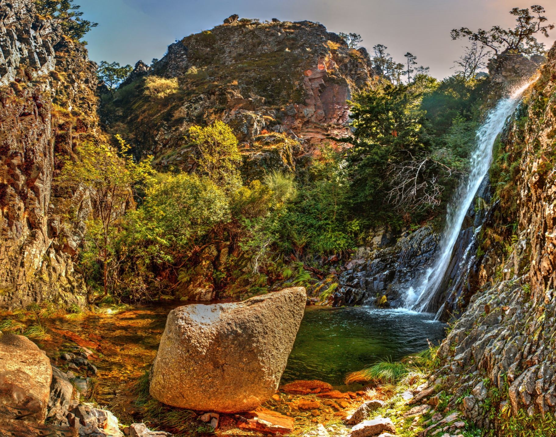 Cascata do Poço do Inferno na Serra da Estrela com queda de água cristalina entre rochas e vegetação outonal