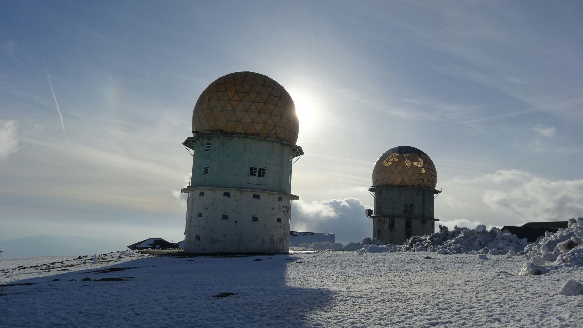 Torres geodésicas no ponto mais alto da Serra da Estrela cobertas de neve com sol a brilhar por trás