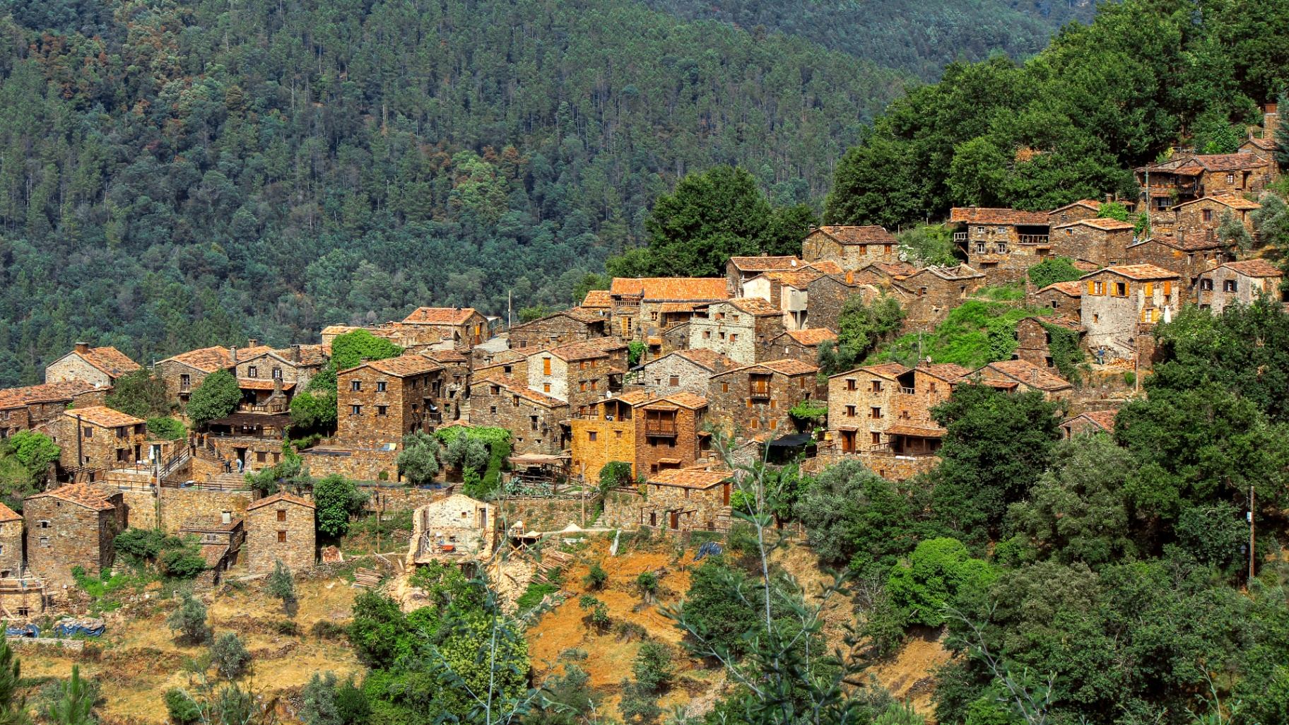 Aldeia do Talasnal na Serra da Lousã com casas de xisto dispostas na encosta da montanha rodeadas por floresta verde